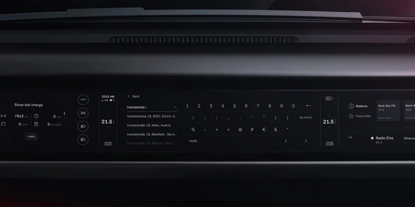 Entering a destination on the infotainment screen — the address field with matching suggestions listed beneath, the on-screen keyboard to its right, climate and media panels either side